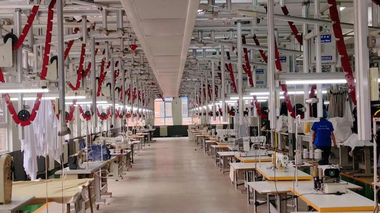 Rows of workstations and textile machinery inside a production area.
