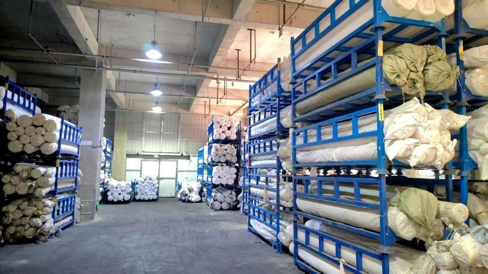 Rolled textiles stored on blue racks inside an industrial storage area.